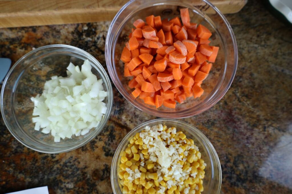 chopped onions carrots and corn in glass bowls