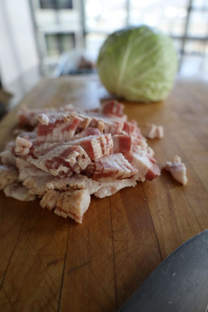 chopped raw bacon and cabbage on a wooden cutting board