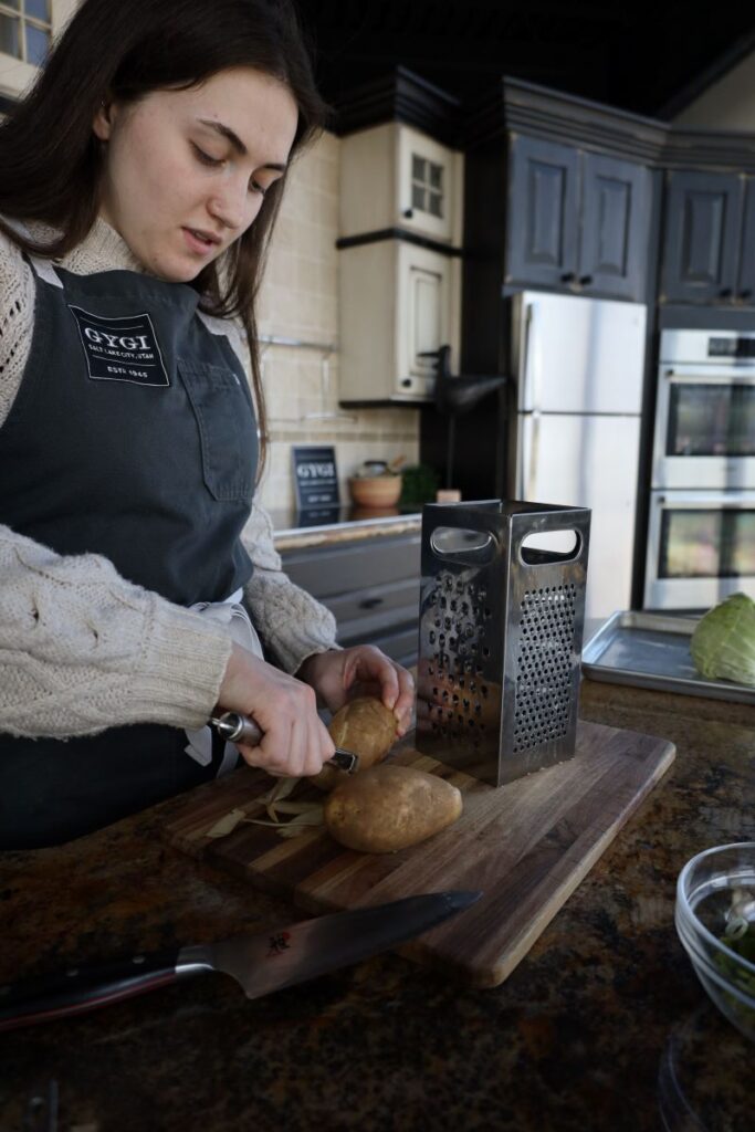 chef peeling potatoes on a cutting board