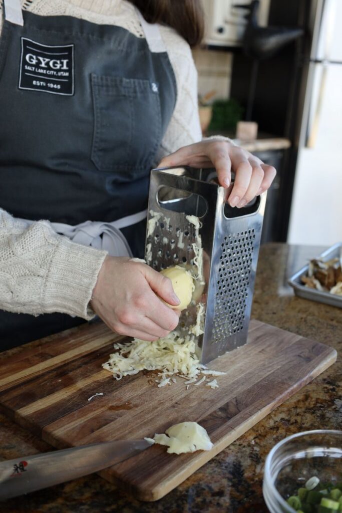 woman using box grater to shred potatoes