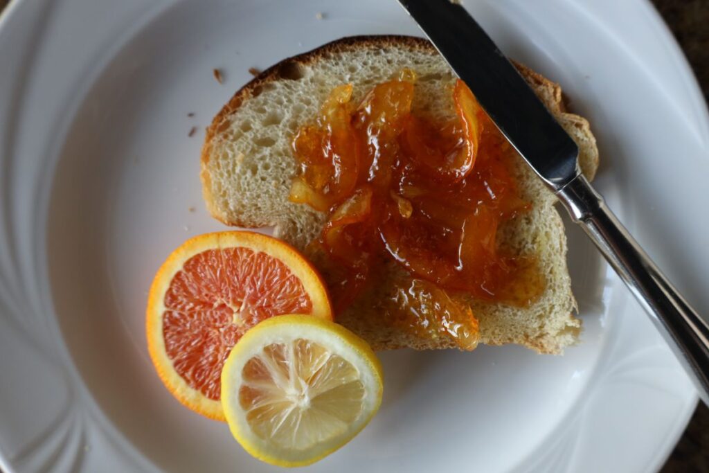 orange marmalade on fresh homemade bread with slices of orange and lemon