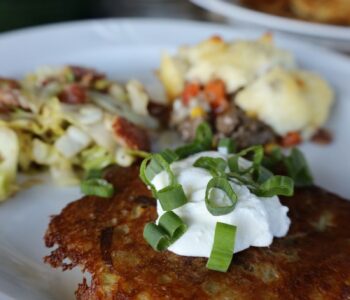 Irish Boxty on a white plate with shepherds pie and cabbage