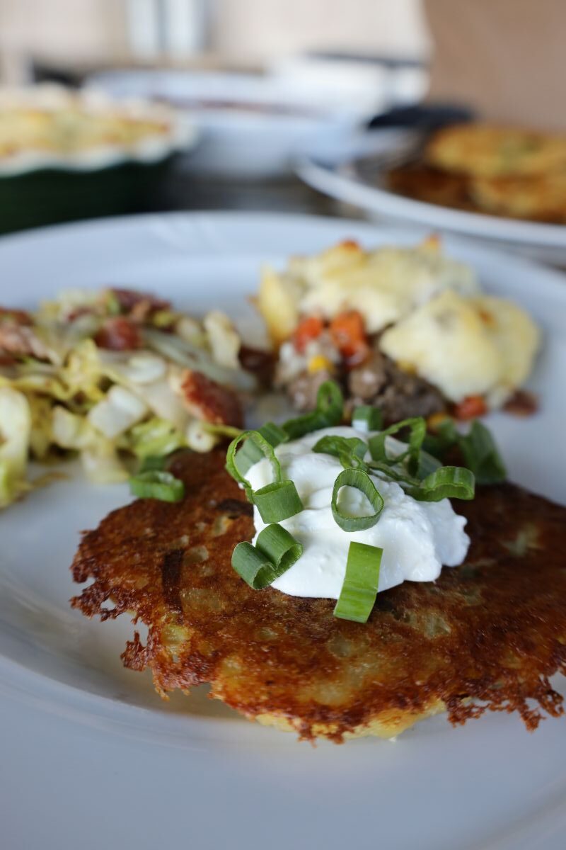 Irish Boxty on a white plate with shepherds pie and cabbage